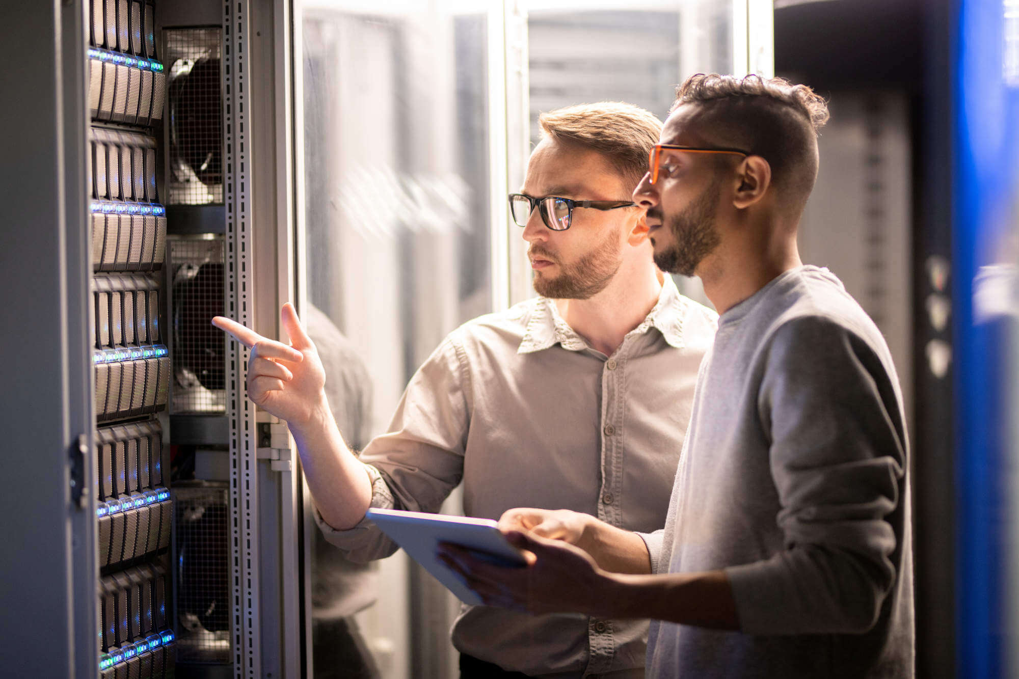 Two data technicians wearing glasses and inspecting a server rack