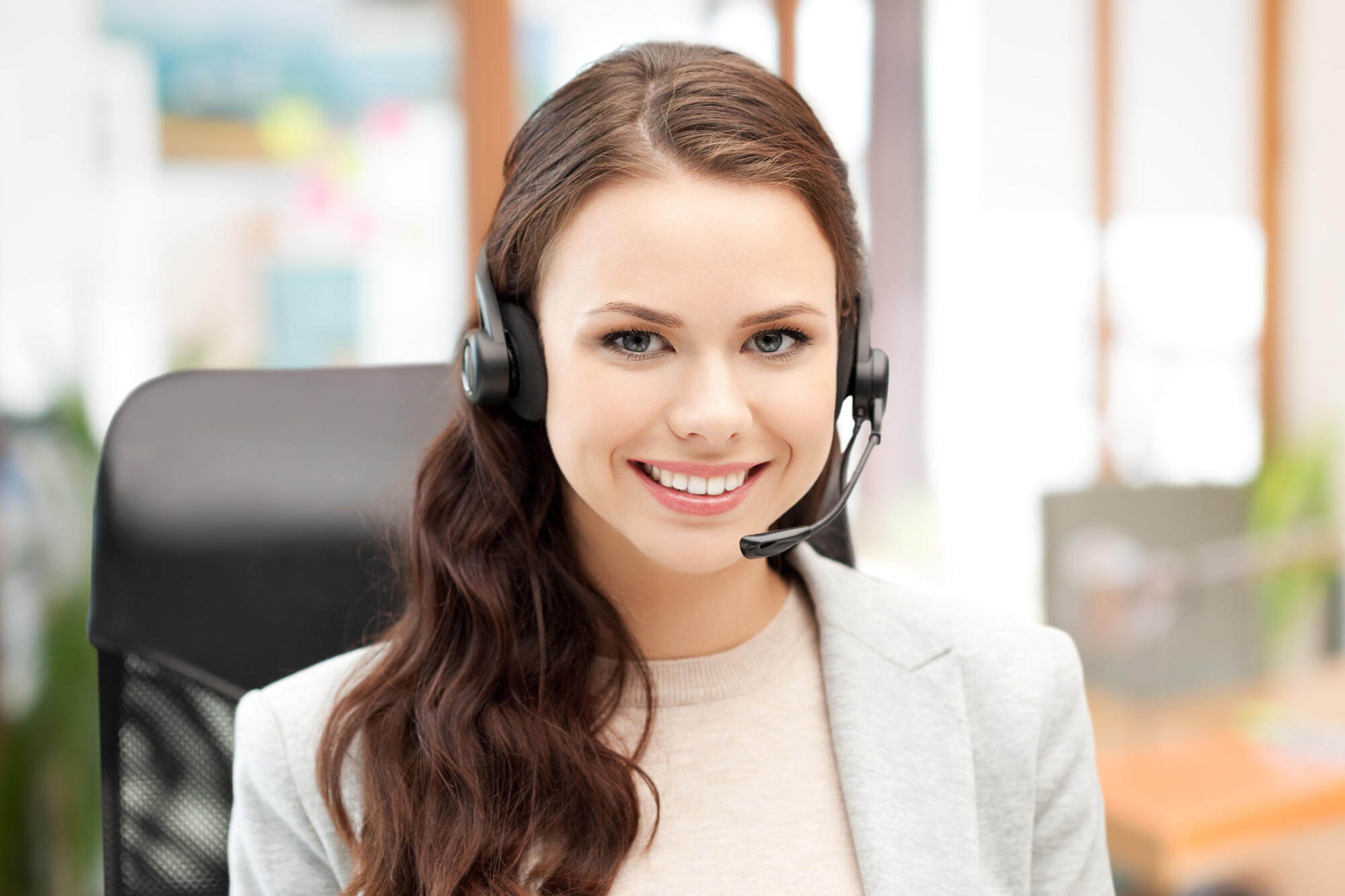 Smiling customer support woman wearing VoIP headset in call center